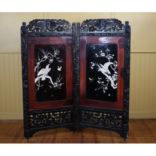 58 - AN ORIENTAL CARVED OAK TWO FOLD SCREEN with black and red lacquer panels overlaid with birds amongst... 