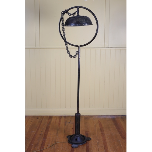 70 - A WROUGHT IRON FLOOR STANDARD LAMP the circular frame with oval shade hung with a link chain above a... 