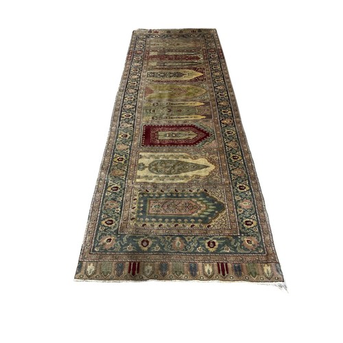 651 - AN ORIENTAL WOOL RUNNER the beige, light blue and wine ground with central panel filled with arches ... 