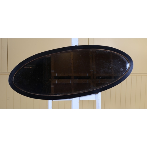 641 - A VINTAGE STAINED WOOD AND GILT MIRROR of oval outline the shaped bevelled glass plate within a moul... 