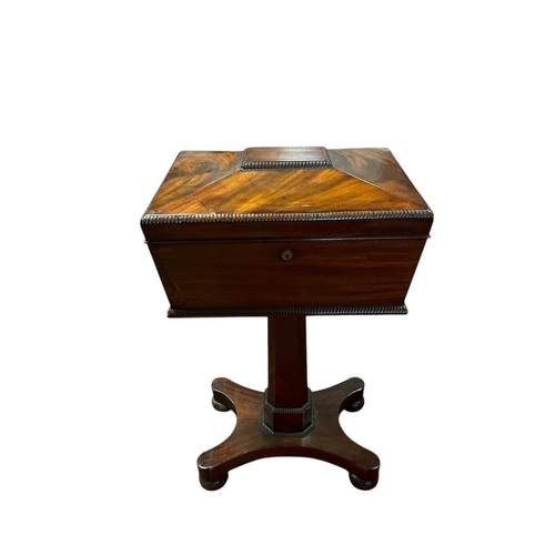 A REGENCY MAHOGANY TEAPOY the rectangular hinged lid containing lidded compartments above a faceted column on a shaped platform base with bun feet and castors 77cm (h) x 40cm (w) x 29cm (d)