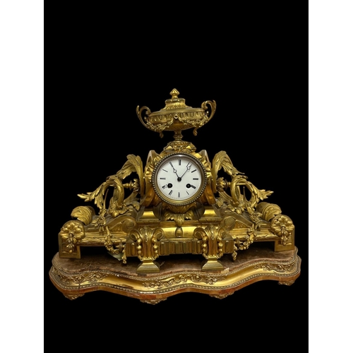 A 19TH CENTURY FRENCH ORMOLU  MANTEL CLOCK the circular drum with enamel dial and Roman numerals surmounted by a neo-classical urn above a scroll platform decorated overall with acanthus leaves and flowerheads raised on a giltwood stand 41cm (h) x 59cm (w) x 27cm (d)