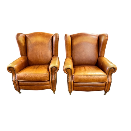 357 - A PAIR OF BROWN HIDE UPHOLSTERED WING LIBRARY ARMCHAIRS with scroll over arms and loose cushions on ... 