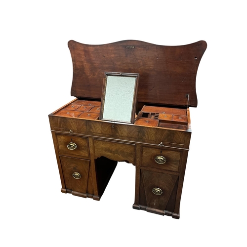 A VERY FINE GEORGIAN MAHOGANY CROSSBANDED DESK / DRESSING TABLE of serpentine outline the hinged lid containing lidded compartments with vanity mirror above a brush and slide with three frieze drawers and one deep drawer containing a zinc liner and one mock drawer flanked by a cupboard on platform support 84cm (h) x 121cm (w) x 66cm (d), 120cm (h) when top opened