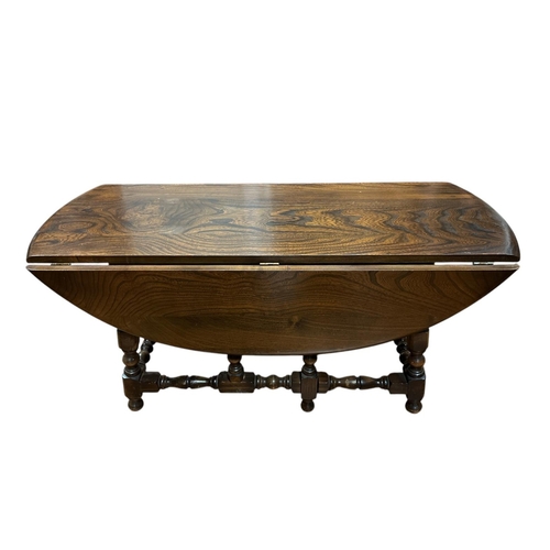 74 - A JACOBEAN STYLE OAK DROP LEAF COFFEE TABLE of oval outline on baluster supports joined by conformin... 
