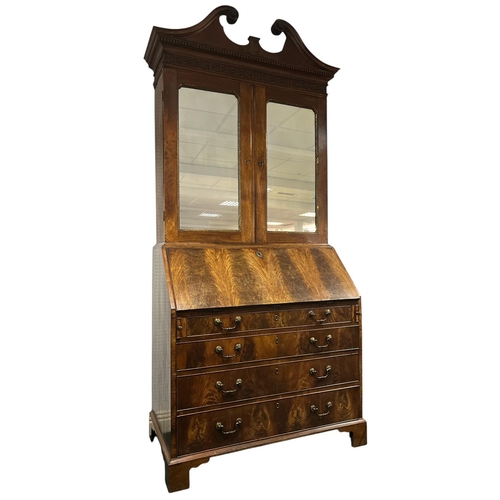 A VERY FINE GEORGIAN MAHOGANY BUREAU BOOKCASE c.1760 the swan neck pediment above a blind fretwork frieze with mirrored doors containing adjustable shelves the hinged writing slope with pigeon holes and drawers above four long graduated drawers with brass drop handles on bracket feet 232cm (h) x 109cm (w) x 58cm (d)