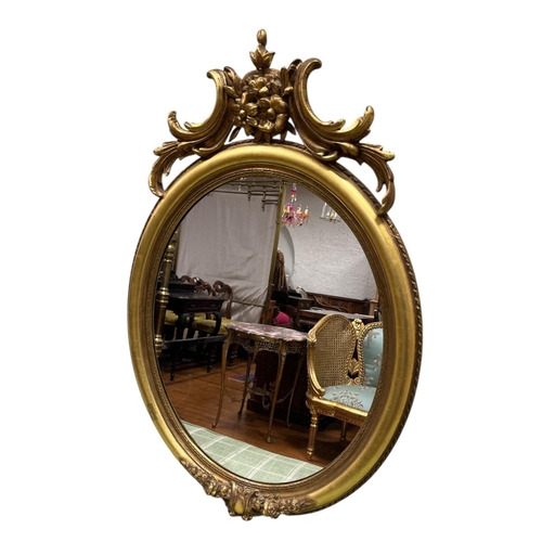 113 - A VINTAGE GILT FRAME MIRROR the oval plate within a moulded frame with foliate and flowerhead cresti... 