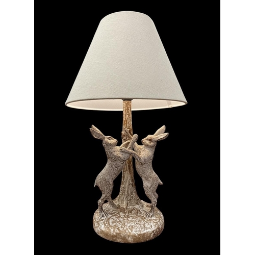 93 - A SIMULATED LIMED WOOD FIGURAL TABLE LAMP with march hares shown standing on a naturalistic base wit... 