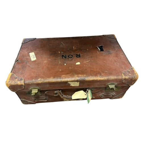 153 - A VINTAGE LEATHER SUITCASE bearing the initials R. O'N. with various tags and transport labels attac... 