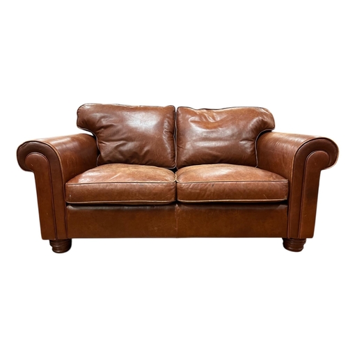 118 - A BROWN HIDE UPHOLSTERED TWO SEATER SETTEE with loose cushions and scroll over arms on turned legs 7... 