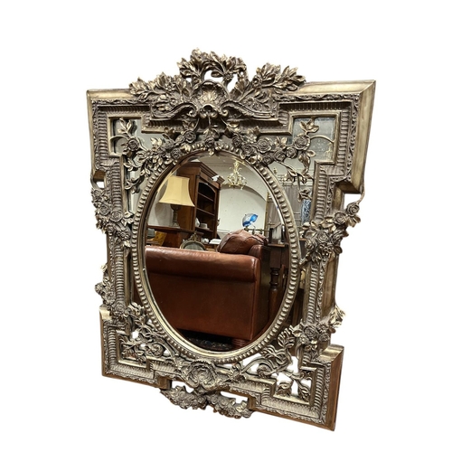 350 - A CONTINENTAL SILVER FRAMED MIRROR the oval bevelled glass plate within a pierced flowerhead and fol... 