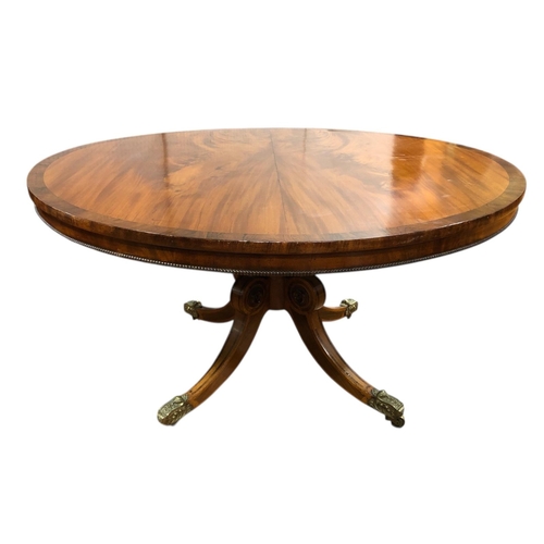 A FINE GEORGIAN MAHOGANY AND ROSEWOOD CROSSBANDED POD TABLE the circular moulded top with gadrooned rim raised on a foliate carved column with quadruped splayed legs with embossed brass caps and castors 70cm (h) x 136cm (d)