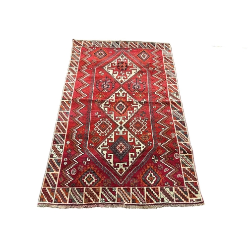 152 - AN ORIENTAL WOOL RUG the wine, light pink and beige ground with central panel filled with serrated p... 