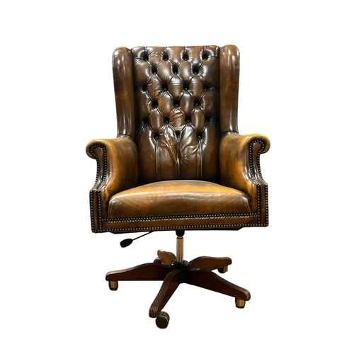 67 - A MAHOGANY AND HIDE UPHOLSTERED WING BACK SWIVEL LIBRARY CHAIR with deep buttoned upholstered back a... 