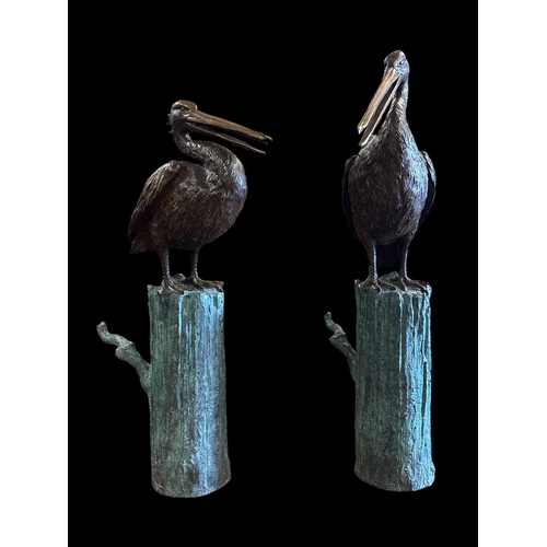 A PAIR OF CAST BRONZE FIGURAL SCULPTURES in the form of pelicans sat atop patinated log plinths 93cm (h)