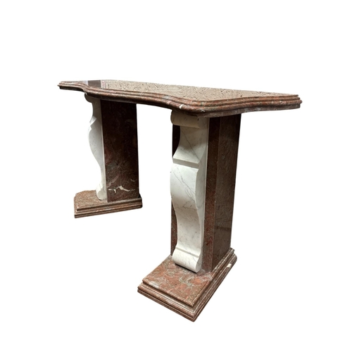 A NEO-CLASSICAL STYLE RED AND WHITE MARBLE CONSOLE the serpentine form thumb moulded three layer top resting on canted supports with contrasted volute brackets set on moulded plinth bases 104cm (h) x 187cm (w) x 59cm (d)