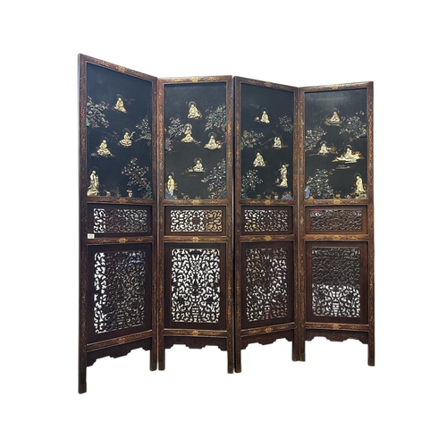A CHINESE LACQUERED BLACKWOOD FOUR FOLD SCREEN 19th century. Qing Dynasty. Solid top panels applied with sixteen carved Buddhist groups above two foliate pierced panels embellished with various hard stone on square tapering supports with brackets the reverse with gilded decoration depicting mountainous and wooded landscapes with figures and buildings Each screen 225cm (h) x 58cm (w)