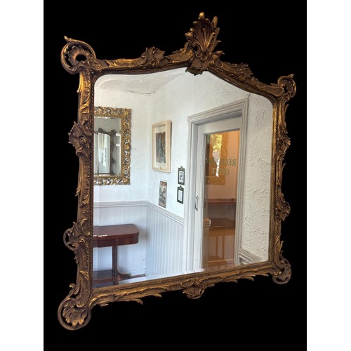 315 - A ROCOCO STYLE GILTWOOD AND GESSO WALL MIRROR the bevelled glass plate with domed top within a confo... 