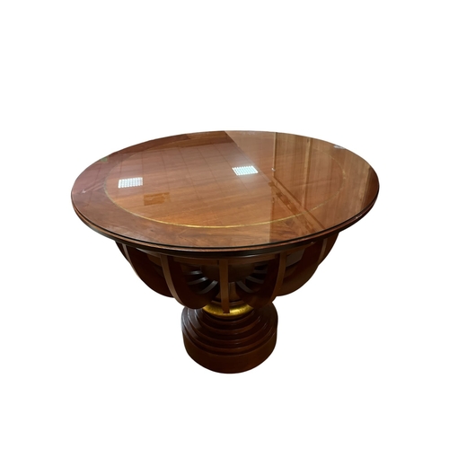 A DESIGNER MAHOGANY CROSSBANDED AND PARCEL GILT CENTRE TABLE the circular top above slatted openwork frieze raised on a circular stepped foot 90cm (h) x 110cm (d)