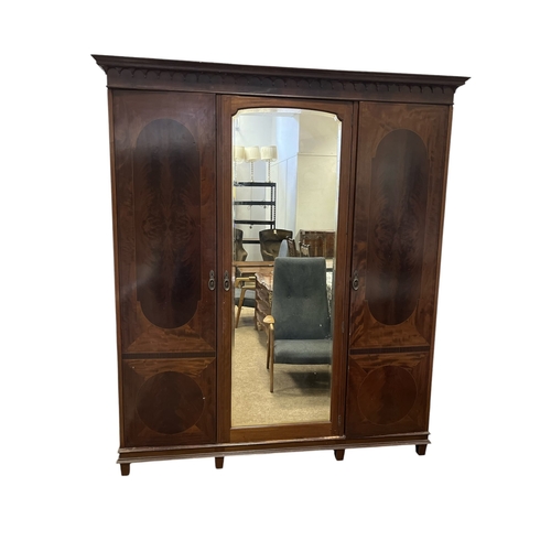 571 - AN EDWARDIAN FLAMED MAHOGANY ARMOIRE the central bevelled glass mirror plate opening onto sliding li... 