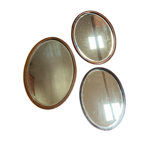 582 - THREE EDWARDIAN INLAID MAHOGANY WALL MIRRORS the largest of oval form with bevelled glass plate with... 