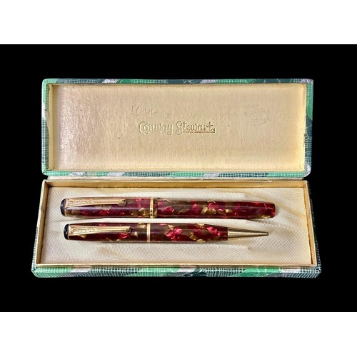 487 - A VINTAGE BURNHAM FOUNTAIN PEN AND MECHANICAL PENCIL SET in a daubed burgundy and gold toned resin c... 