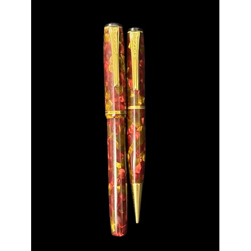 487 - A VINTAGE BURNHAM FOUNTAIN PEN AND MECHANICAL PENCIL SET in a daubed burgundy and gold toned resin c... 