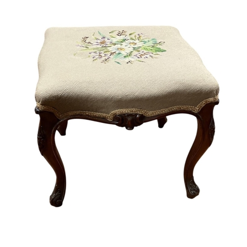 379 - A 19TH CENTURY CARVED MAHOGANY FOOTSTOOL of serpentine outline the shaped seat with needlework uphol... 