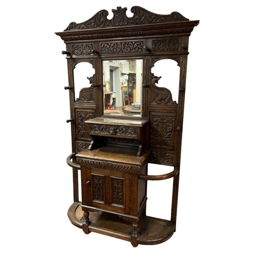 409 - A LATE 19TH CENTURY JACOBEAN STYLE CARVED OAK HALLSTAND carved overall with foliage and figural mask... 