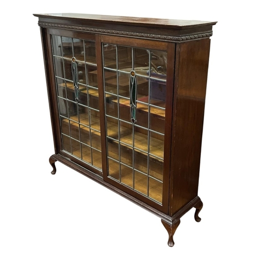 411 - A MID-CENTURY OAK BOOKCASE of rectangular outline the shaped top above a pair of lead glass and colo... 