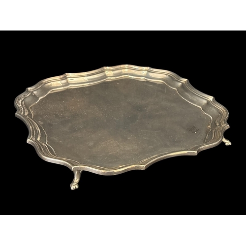 758 - A STERLING SILVER SALVER the shaped and moulded rim raised on four hooved feet Chester 1927 530g (17... 