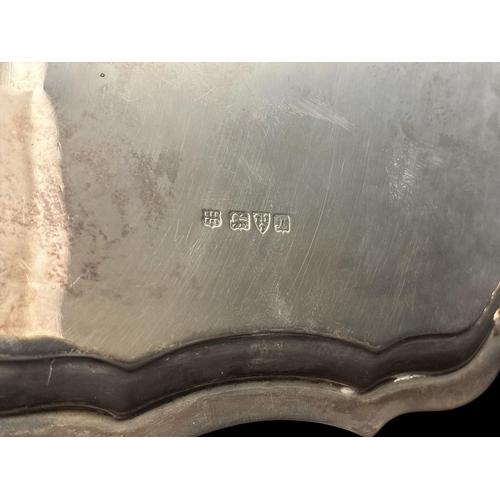 758 - A STERLING SILVER SALVER the shaped and moulded rim raised on four hooved feet Chester 1927 530g (17... 