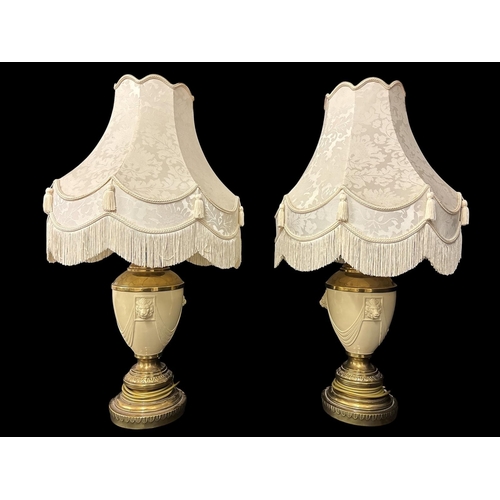 111 - A PAIR OF VINTAGE GILT BRASS AND ENAMELLED TABLE LAMPS modelled as urns with lion masks and linen dr... 
