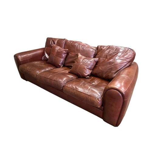 533 - A DURESTA HIDE UPHOLSTERED THREE SEATER SETTEE with scroll over arms and loose cushions on moulded l... 