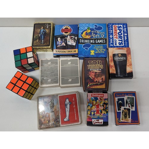 1076 - An Assortment Of Playing Cards And Rubik Cubes. Simpsons, Guiness