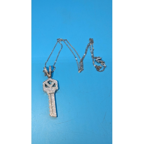 516 - Silver key pendant pave set with over 100 white round cubic zirconia on a silver chain.