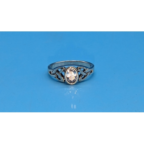 527 - Silver ring, set with an oval white cubic zirconia and celtic patterned shoulders