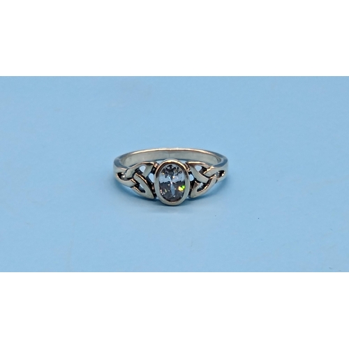 527 - Silver ring, set with an oval white cubic zirconia and celtic patterned shoulders