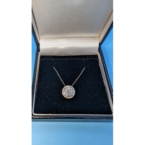 585 - Round brilliant diamond cluster pendant set in 10ct white gold on a 10ct white gold chain.  Boxed.  ... 