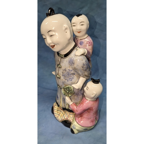 64 - An Oriental figurine of a man playing with children -32cm tall