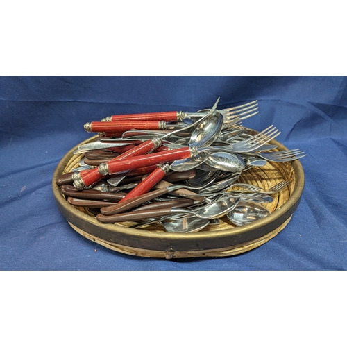 704 - A Selection of stainless steel Italian cutlery and others in basket.   From the country estate.