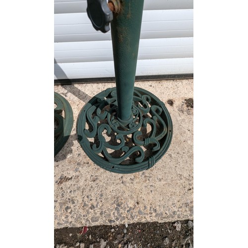 883 - A Pair Of Cast Metal Parasol Bases And 2 Green Parasols