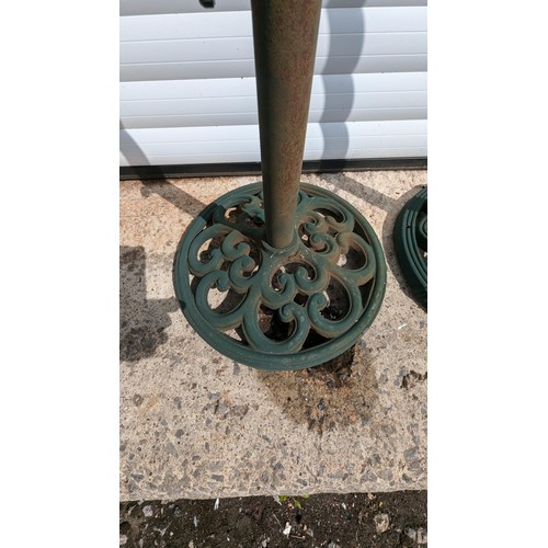 883 - A Pair Of Cast Metal Parasol Bases And 2 Green Parasols