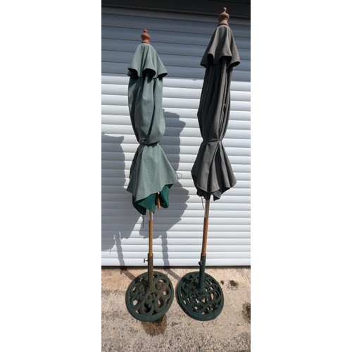 883 - A Pair Of Cast Metal Parasol Bases And 2 Green Parasols