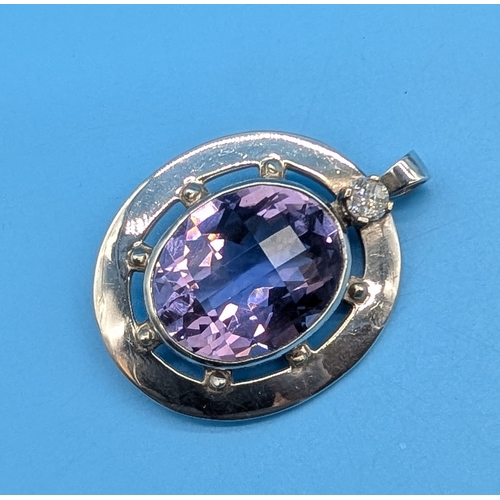 DIAMOND, SILVER AND AMETHYST PENDANT
A substantial silver pendant featuring a large oval checkerboard-faceted amethyst with a vibrant lilac hue, bezel-set within an open circular mount and accented by a single round brilliant-cut diamond of approximately 0.30ct, VS2 clarity and H/I colour. A custom made piece. Total gross weight of approximately 19.58g.
