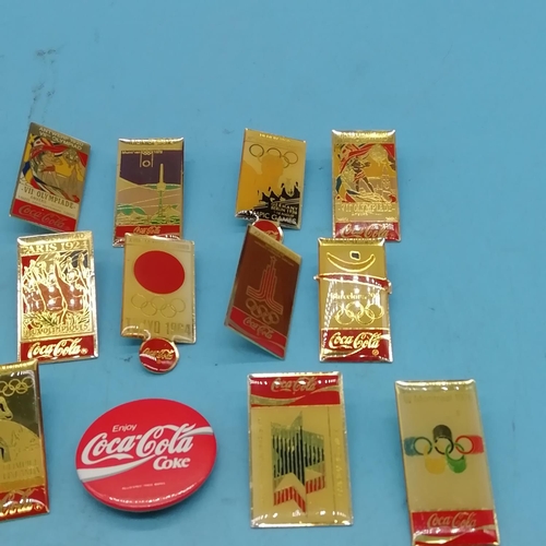 128 - Coca Cola Olympic Pins (13) plus a Coca Cola Badge.