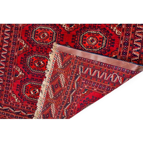 273 - A RED HAND KNOTTED WOOL RUG FROM BOKHARA, UZBEKISTANA Red Hand Knotted Wool Rug From Bokhara, Uzbeki... 