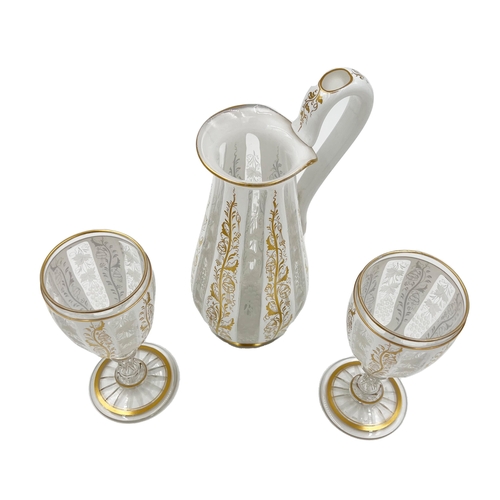 3 - BOHEMIAN GLASS EWER AND CUPS WITH GILT HIGHLIGHTS A Bohemian glass ewer accompanied by two cups... 