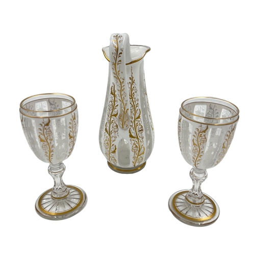 3 - BOHEMIAN GLASS EWER AND CUPS WITH GILT HIGHLIGHTS A Bohemian glass ewer accompanied by two cups... 