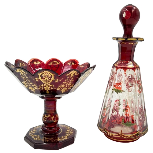 58 - GILDED BOHEMIAN GLASS TAZZA AND BOTTLEExperience the radiance of ruby with this set featuring two gi... 